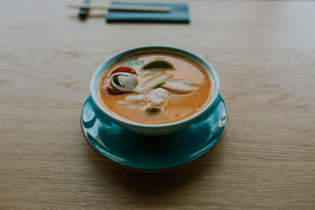 A high angle shot of a beautiful blue plate filled with orange soup with vegetables - perfect for a food blogの写真素材