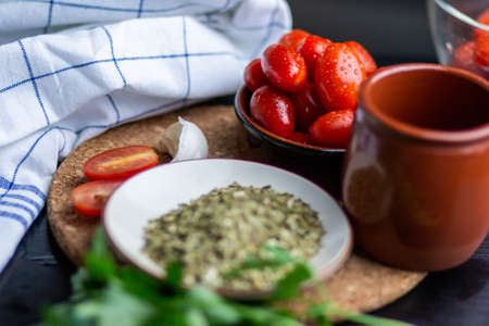 The tomatoes next to a cup, greens and a plate of condimentsの写真素材
