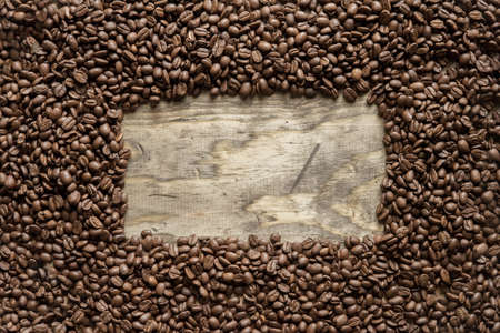 An overhead shot of a coffee beans frame over a wooden surface great for background or writing textの写真素材