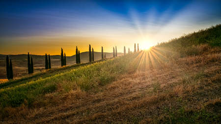 A breathtaking low angle shot of the sunrise in the bright blue sky behind a hillの写真素材