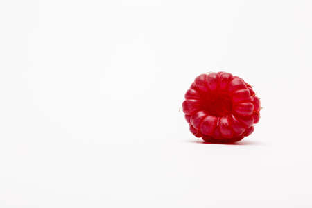 A closeup shot of an isolated raspberry on a white background - perfect for a food blog