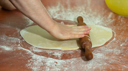 A close up shot of a person preparing the dough with a rolling pin