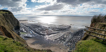 A high angle shot of a beautiful seashore under the hills and the cloudy sky in the backgroundの写真素材