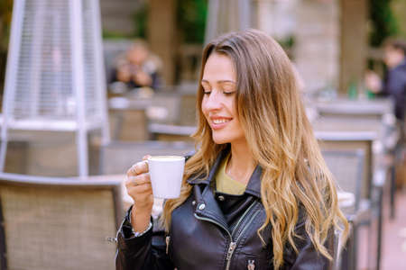 A pretty blonde female drinking coffee in a cafe in the early morning isolated on a blurred...