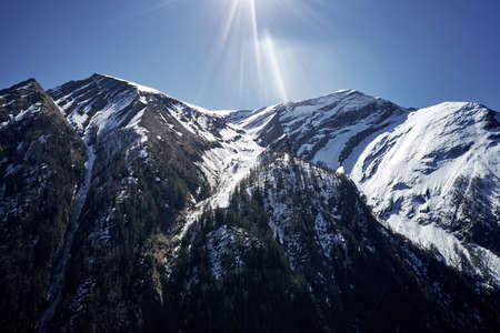 A beautiful low angle shot of a mountain with snow covering the peak and the sky in the backgroundの写真素材