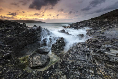 A horizontal shot of water splashing to the mountains during sunset in Cornwall, UK