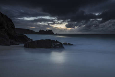A dark mysterious scenery of the ocean and rocks surrounding it in Porthcurno, Cornwall, UK