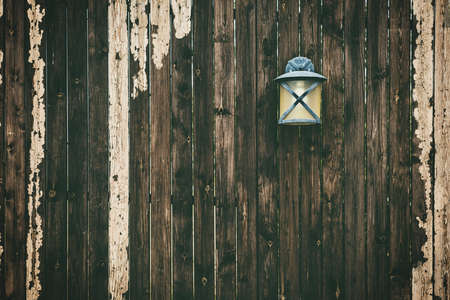 A closeup shot of a black metal sconce lamp on an old wooden fenceの写真素材