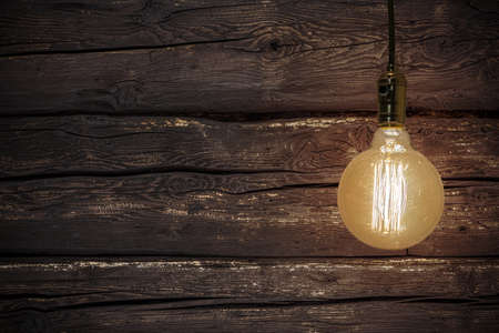 A vintage light bulb isolated on a wooden background - perfect for a backgroundの写真素材