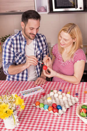 The beautiful couple smiling and painting the easter eggsの写真素材
