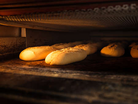 A closeup of raw bread loaves in the oven under the lightsの写真素材