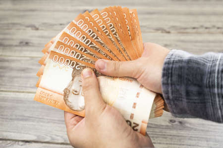 A high angle shot of person counting banknotes over a wooden table