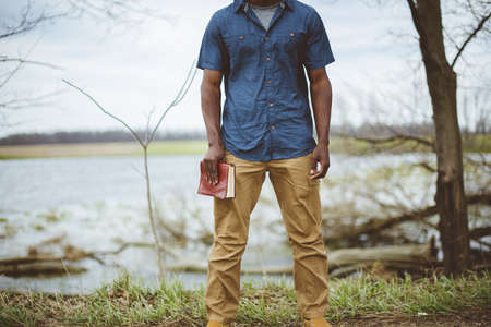 A closeup shot of a male holding the bible while standing with a blurred background