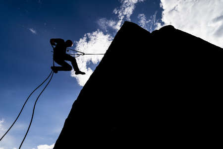 A silhouette of a hiker in an extremely dangerous pose trying to find new adventuresの写真素材
