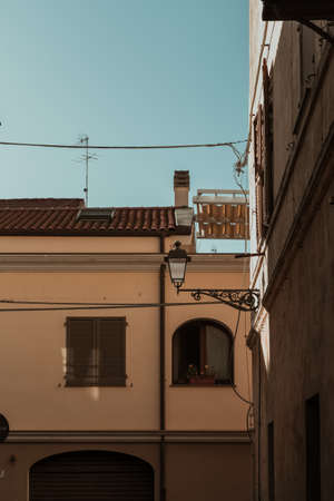 A vertical shot of buildings with a lamp post attached to a wall and a blue sky in the backgroundの写真素材