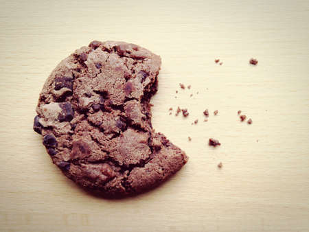 A closeup shot of bitten chocolate cookie on wooden backgroundの写真素材