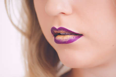 A vertical closeup shot of a female wearing purple and yellow lipstick - great for a makeup articleの写真素材