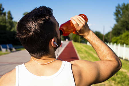 A shallow focus shot of a young male drinking water for running in the parkの写真素材