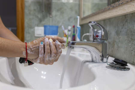 A female washing her hands with soap in the sink - importance of washing hands during the COVID-19...