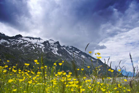 A low angle shot of a tall mountain covered with snow under a cloudy skyの写真素材