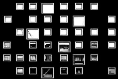 A black wall featuring blank frames and greyscale photos of different places