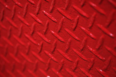 A closeup shot of a painted red metal texture with unique patterns as a beautiful backgroundの写真素材