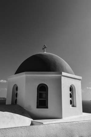 A vertical greyscale shot of a chapel dome with a cross under the peaceful skyの写真素材