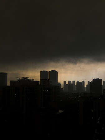 A stunning shot of a silhouette of a city with a dark and cloudy skyの写真素材