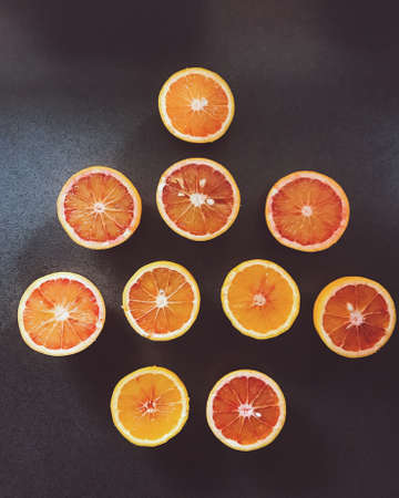 A vertical high angle shot of sliced oranges on a black surface - great for a creative wallpaperの写真素材