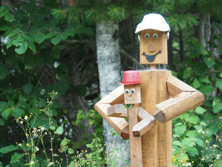 A closeup shot of a cute wooden carving with the form of toys surrounded by green trees during daytimeの写真素材