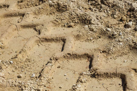 A close up shot of wheel or tire tracks on sand
