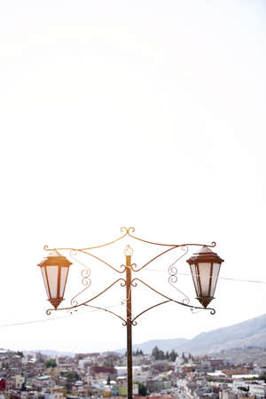 A vertical shot of a vintage street lamp with blurred buildings in the backgroundの写真素材
