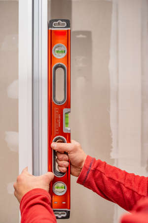 A vertical shot of a male holding an engineering ruler for measuring the frame of a window