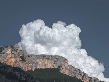A beautiful shot of a cliff with a cloud in a blue sky in the backgroundの写真素材
