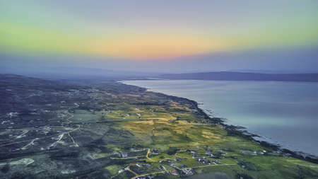 An aerial photography shot  of a valley and a lake under the colorful evening sky