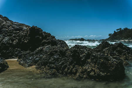 The ocean waves hitting the big rocks at the shoreの写真素材