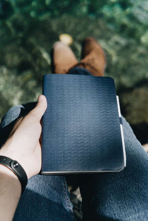 vertical shot of a person holding a black notebook