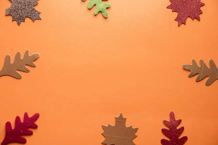 An overhead shot of cut out leaves over an orange surface great for background or writing textの写真素材
