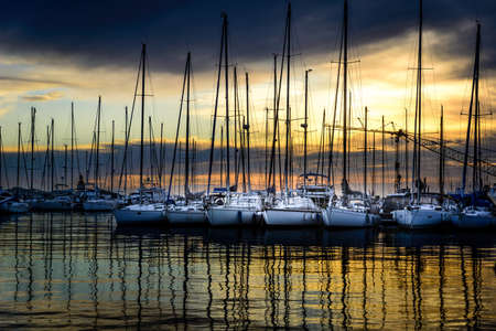 A horizontal shot of modern white yachts parked next to each other in the docks during sunsetの写真素材