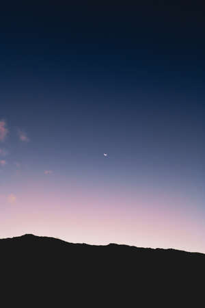 A low angle shot of the moon in the colorful night sky