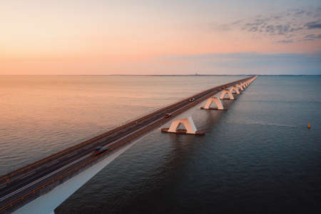 A long bridge going over the magnificent ocean under the beautiful colorful skyの写真素材