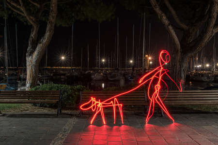 A light effect of a person walking a dog with steel wool effect in the park in Italy at nighttimeの写真素材
