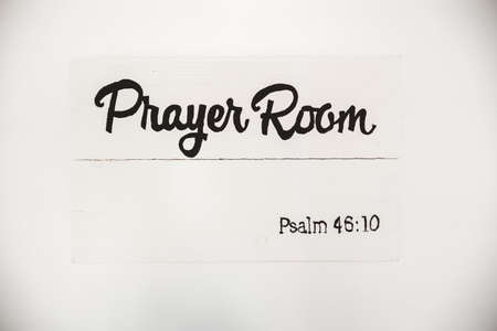 A closeup shot of a white wooden sign with a bible quote written on it on a white surfaceの写真素材