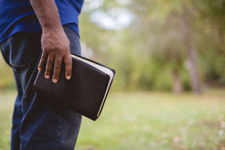 A closeup shot of a male holding the bible with a blurred background
