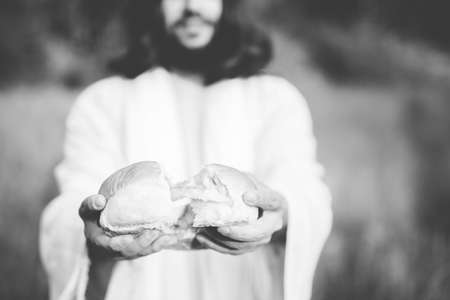 A biblical scene - of Jesus Chris separating the bread with blurred background in black and whiteの写真素材