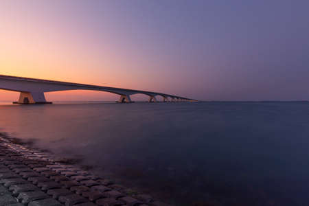 A bridge over the sea with a beautiful sky in the background at sunsetの写真素材