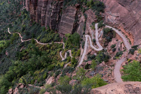 A beautiful high angle scene of a winding path in the rocky mountains and forest below