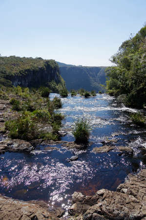 A vertical shot of green mountainous scenery with a small lake under the clear sky