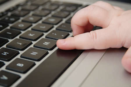 A closeup shot of a baby's hand on a computer keyboardの写真素材