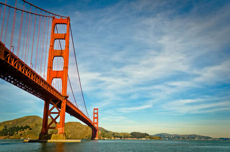 A low angle shot of the golden gate bridge with a blue cloudy sky in the background at daytimeの写真素材